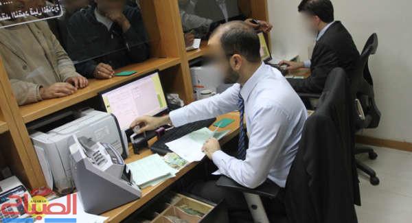 A Palestinian staff of the Islamic National Bank facilitates financial transactions for customers in Gaza city | جريدة الصباح